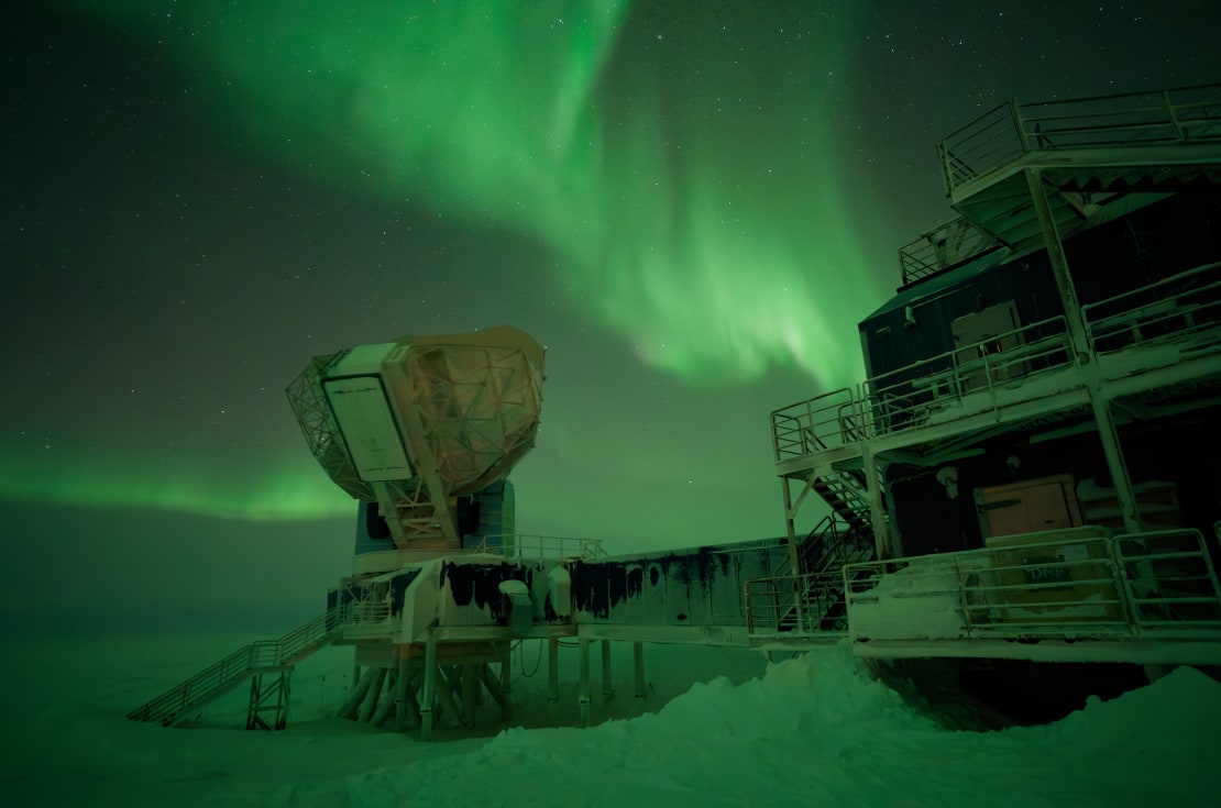 Large, bright green auroras across sky above South Pole Telescope, and reflected on surface ice, too.