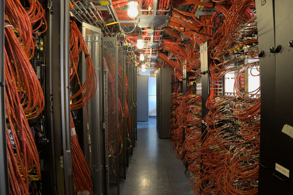 View of IceCube Lab server room, with racks and cables lining both sides of corridor.