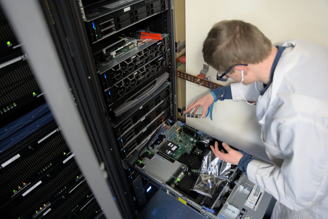 Winterover bent over computer rack in the IceCube Lab.