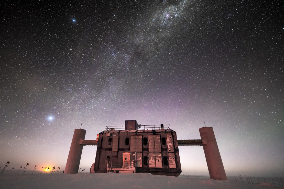 Front view of the IceCube Lab at twilight, stars in sky and sunlight just barely on horizon.