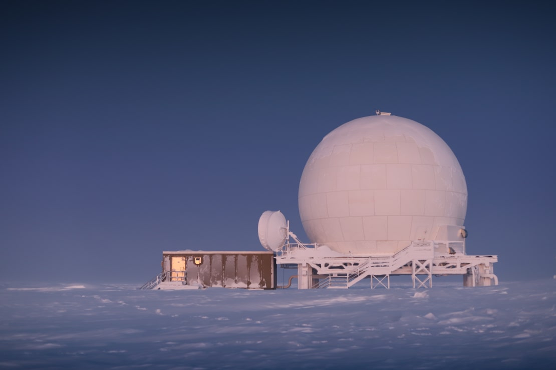 View of satellite dome at South Pole sunrise, with sunlight coming from behind.