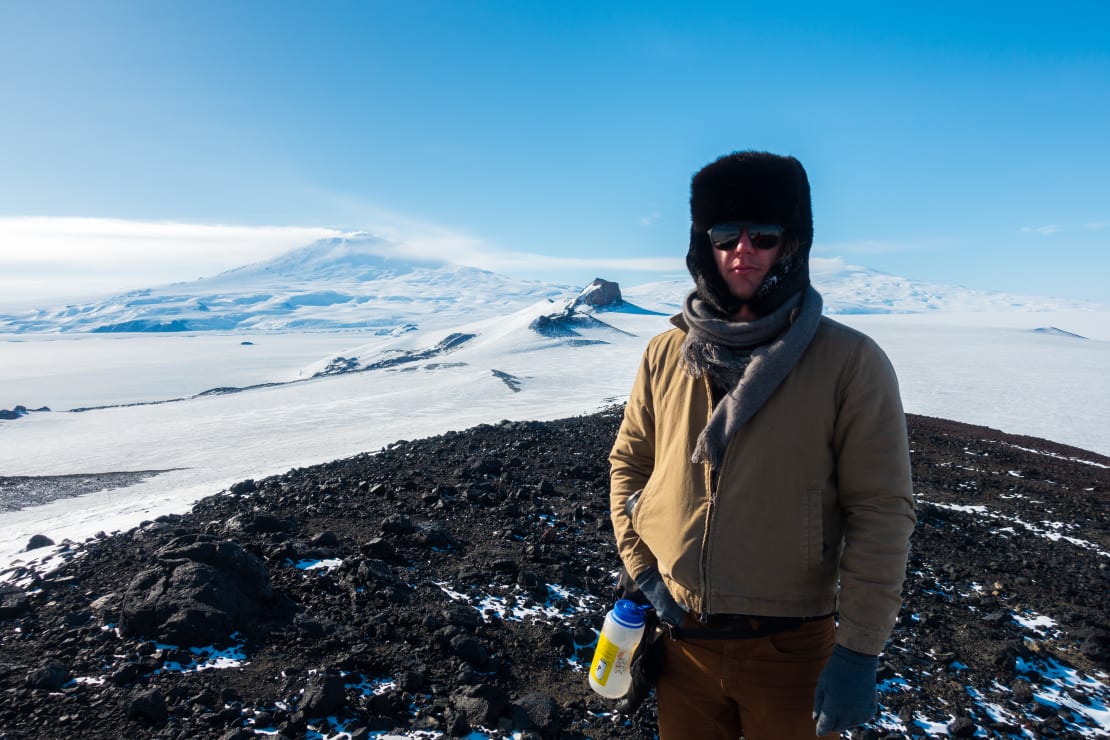 A man standing in front of a snow capped volcano