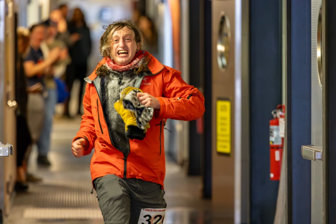 Person inside the South Pole station as they finish full marathon race, with pained expression.