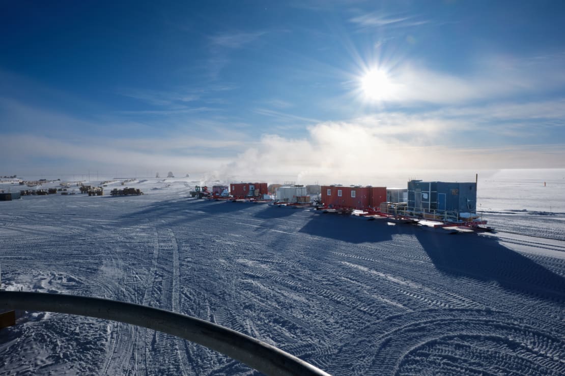 A line of cargo containers under a bright sun at the South Pole.