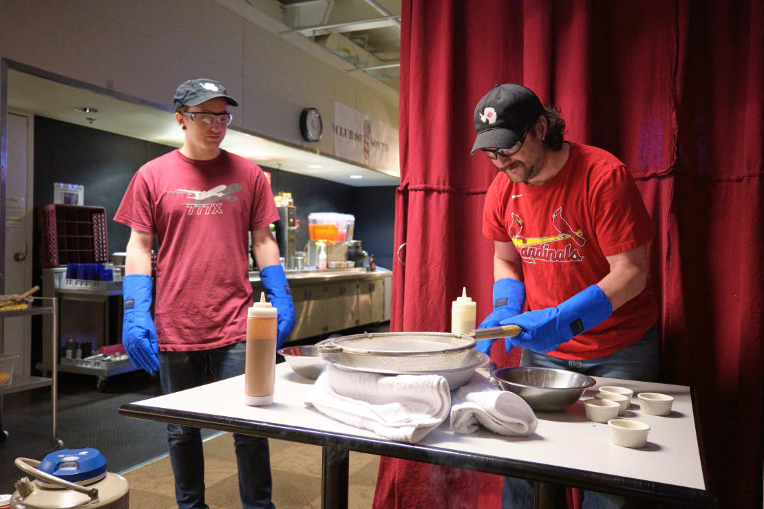 Two people with long protective gloves on working at a table.