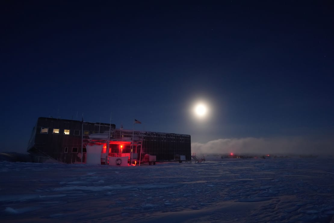 A bright moon above the South Pole station in shadow.