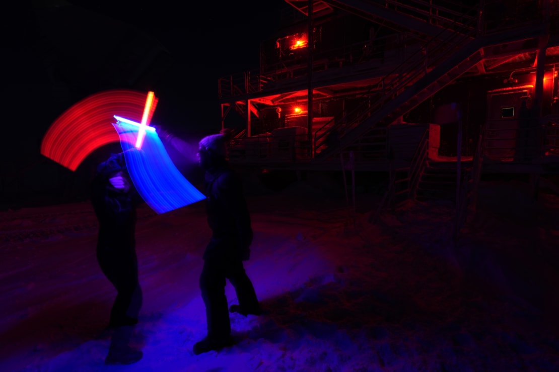 Very dark photo except for a bright X formed by clashing lightsabers along with swaths of blue and red from the sabers’ paths.