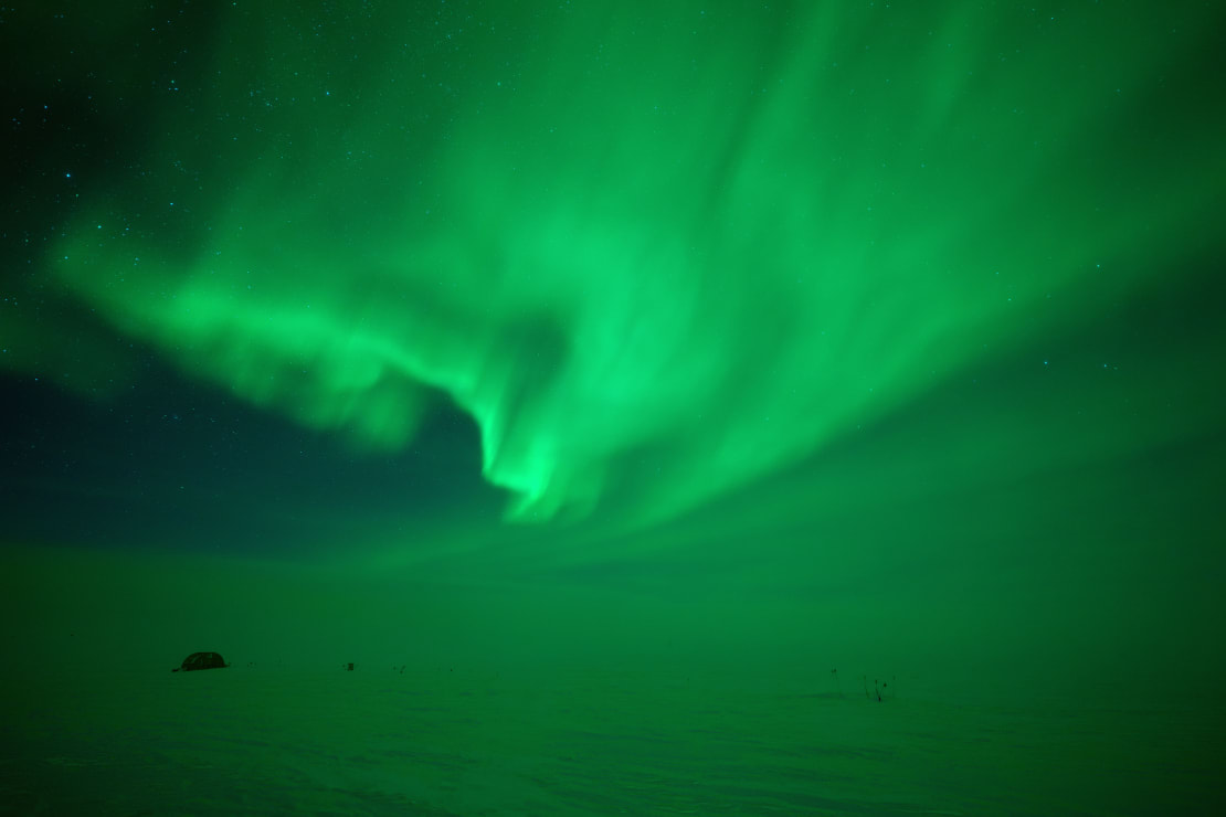 Sky filled with swirling green aurora.