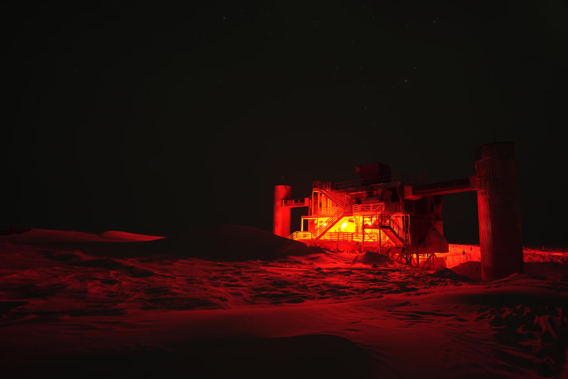 The IceCube Lab illuminated in red exterior lighting, black sky.