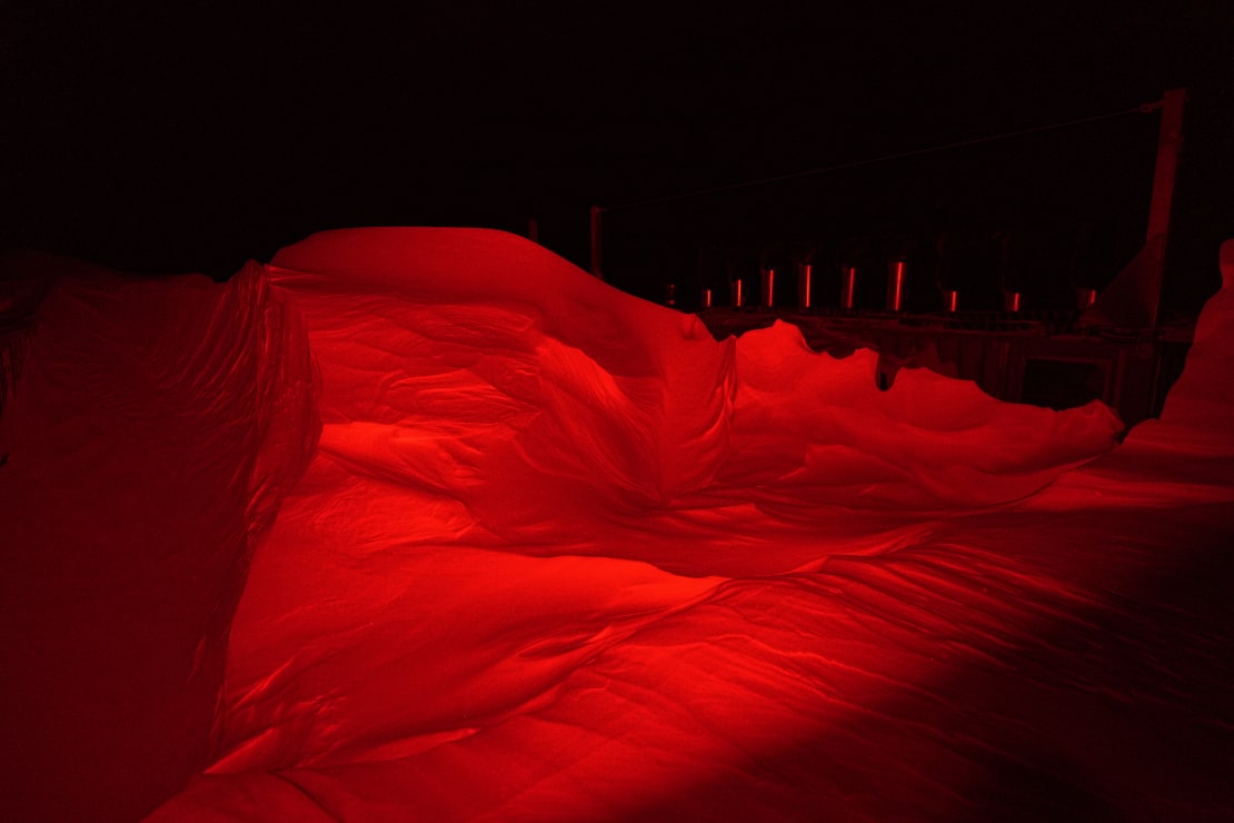 Large snowdrift brightly illuminated in red, all else dark in background.
