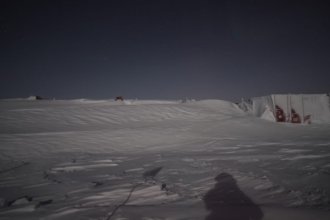 South Pole storage containers barely visible behind large snow drifts.