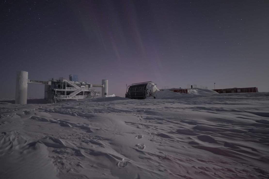 View of thhe IceCube Lab, hose reel and storage containers nearby, faint light in the sky.