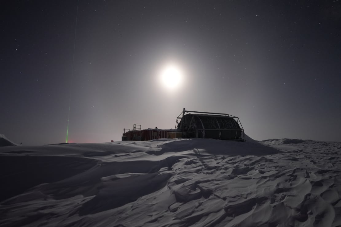A bright moon above a large hose reel in shadow at the South Pole.