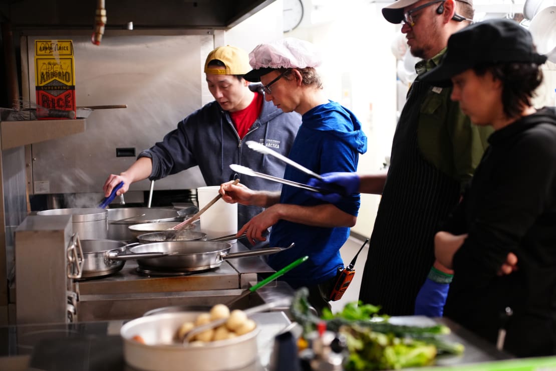 Side view of group cooking at industrial stove.