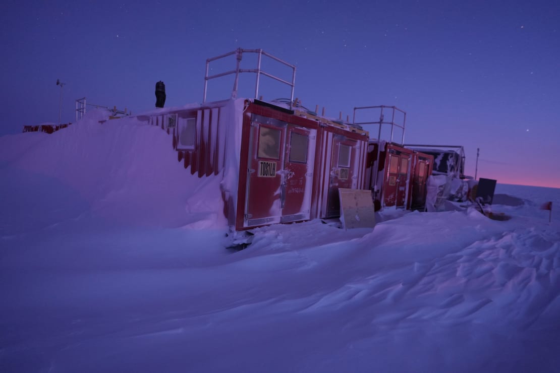 Storage building, frosty and with snow drifts up the sides, at South Pole twilight.