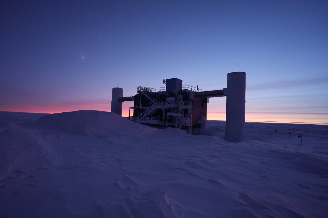 The IceCube Lab in shadow at twilight, with orange light just beginning to appear on horizon.