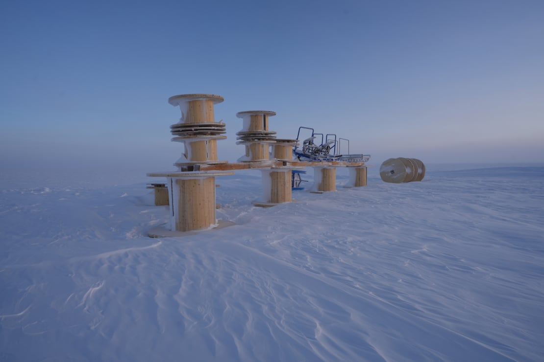 Stacked collection of large empty cable spools out on the ice at the South Pole at sunrise.