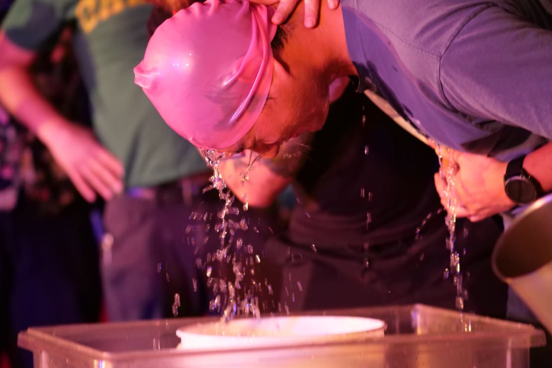 Side view of person’s head dripping with water after being submerged in bucket of water.