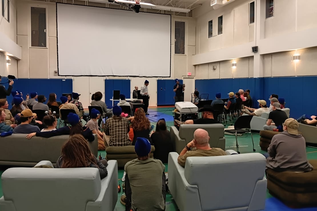 People assembled in South Pole gym, on sofas and chairs lined up for large-screen film viewing.