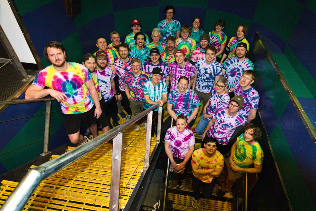 Group photo in stairwell of station members all wearing tie-dyed shirts.