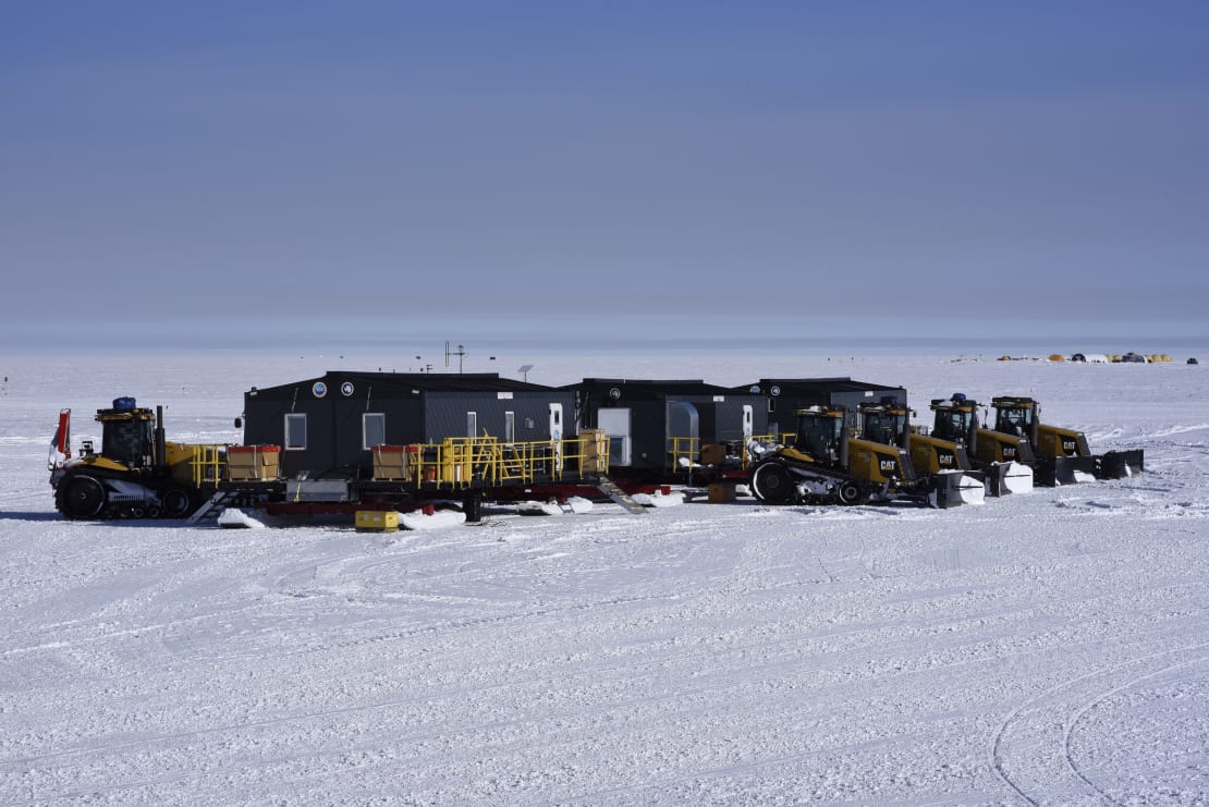 The South Pole traverse living quarters, structures in line on sleds with windows and doors discernible.
