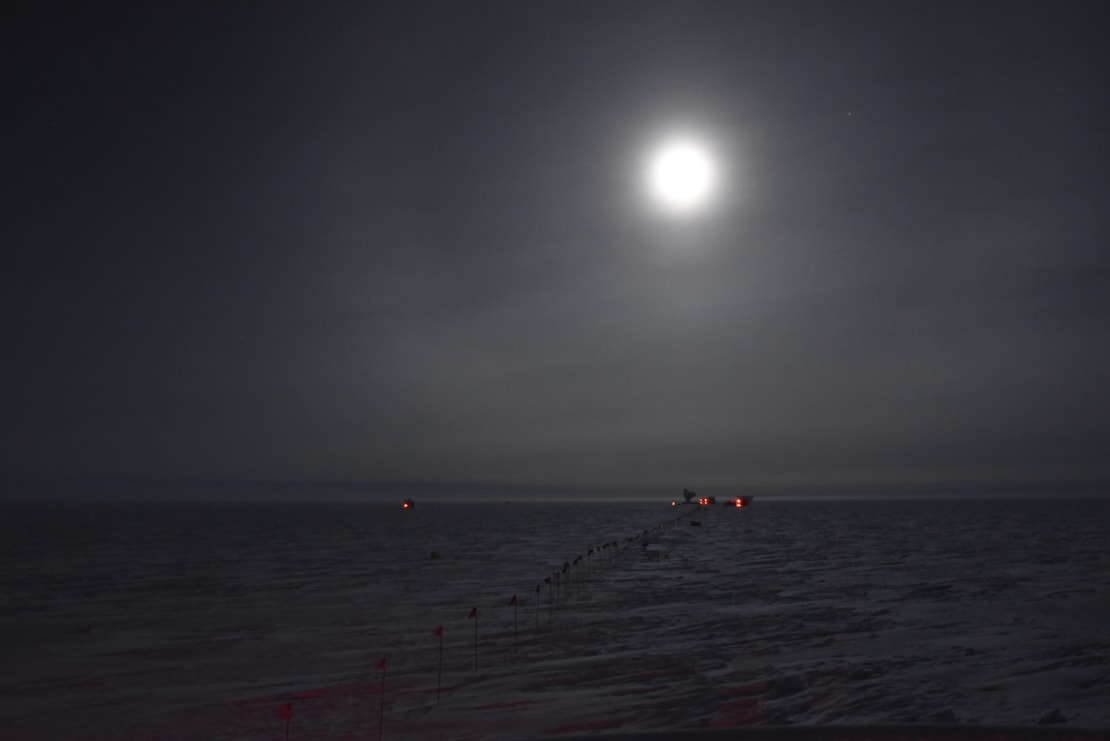 Full moon in dark sky over Dark Sector building on distant horizon.