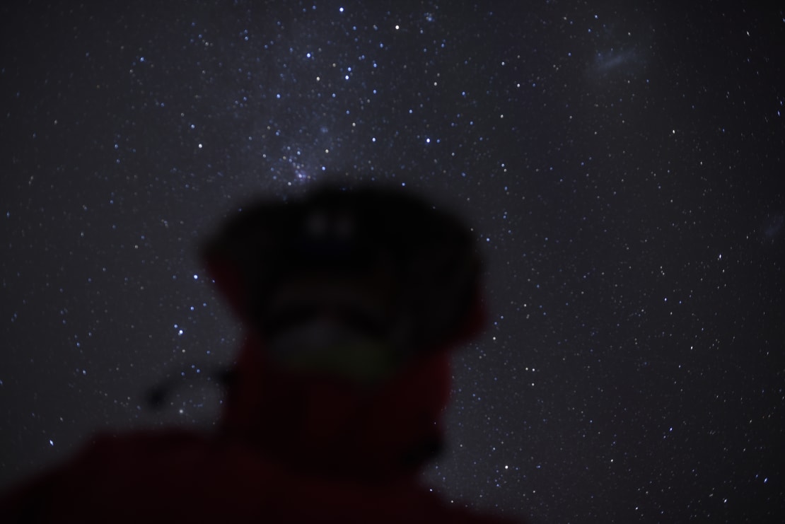 Starry sky with blurry shadow in foreground from someone taking a selfie.