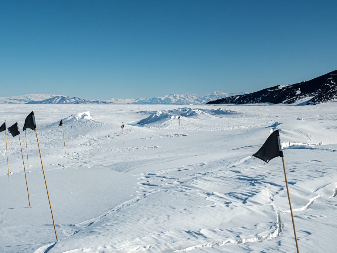 Black flags marking unsafe spots along sea ice trail.