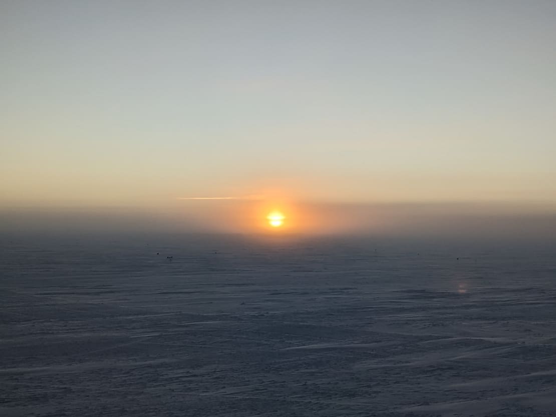 Orange sun low on horizon at the South Pole.