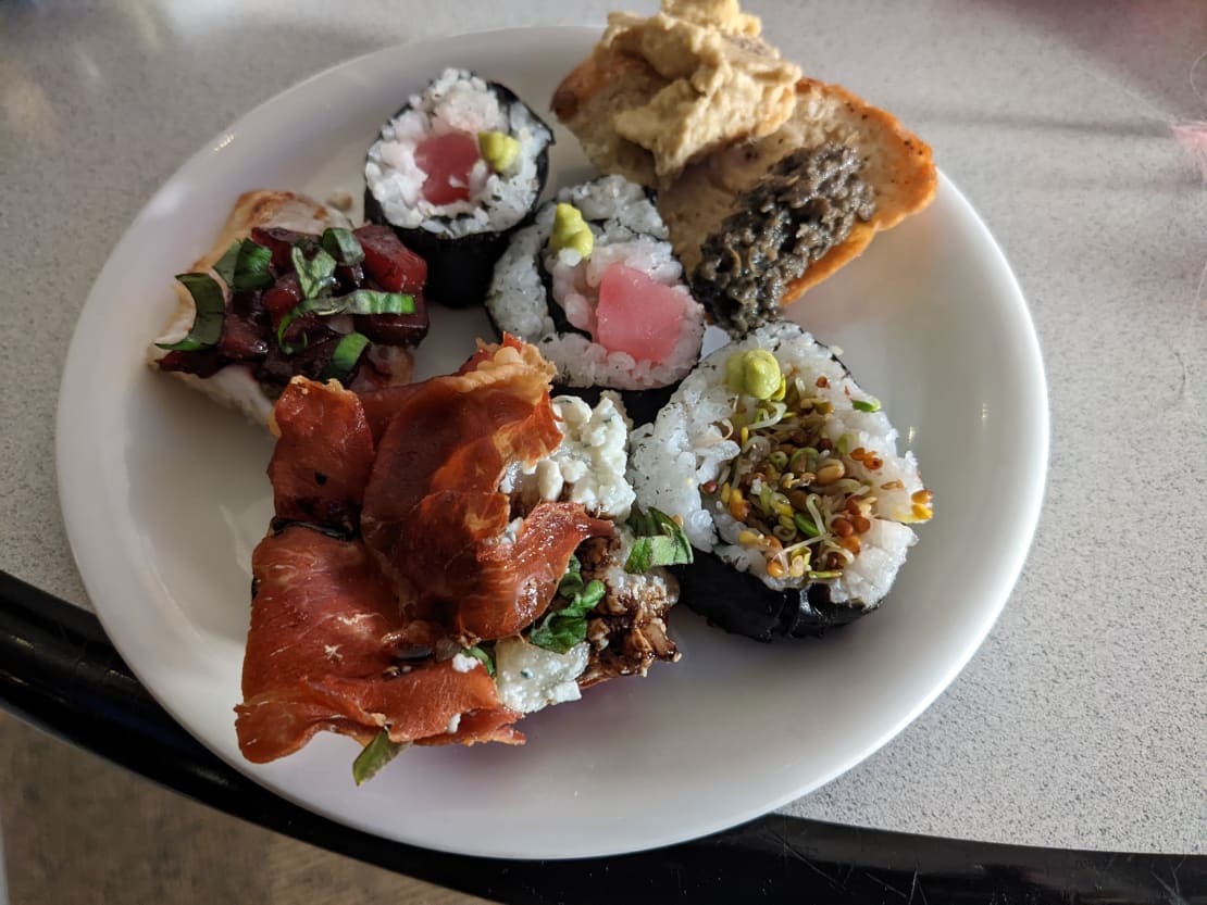 Close-up of plate of appetizers, including some sushi rolls.