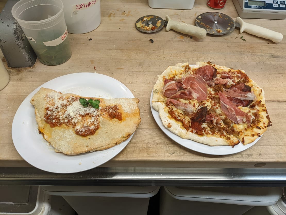 Close-up of a plated calzone and pizza.