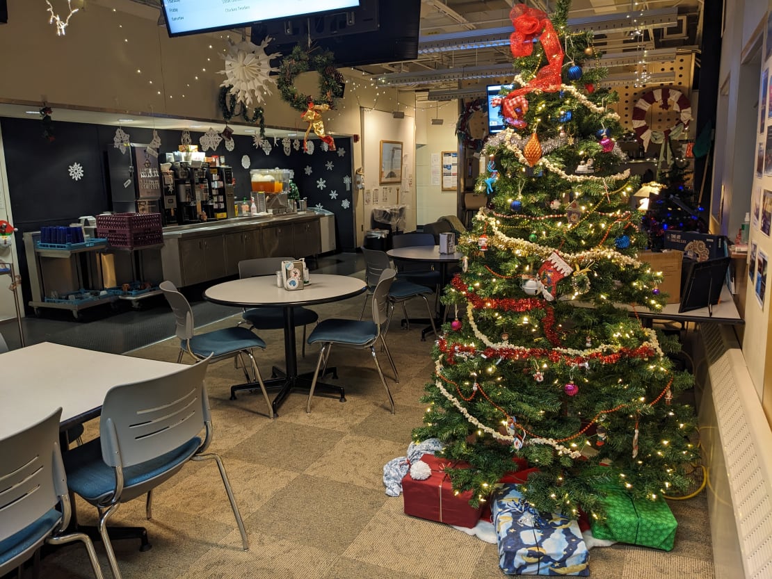 A decorated Christmas tree with presents below it in the South Pole station galley.