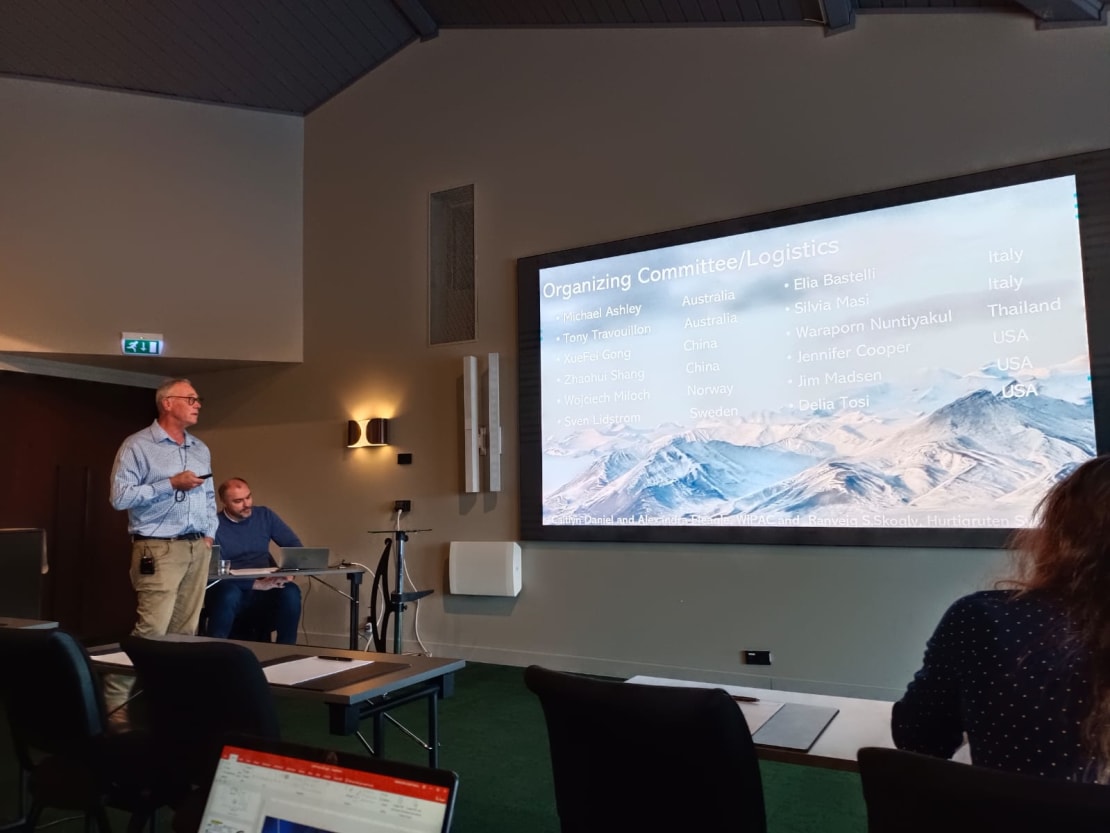 A man giving a talk in front of people in a room