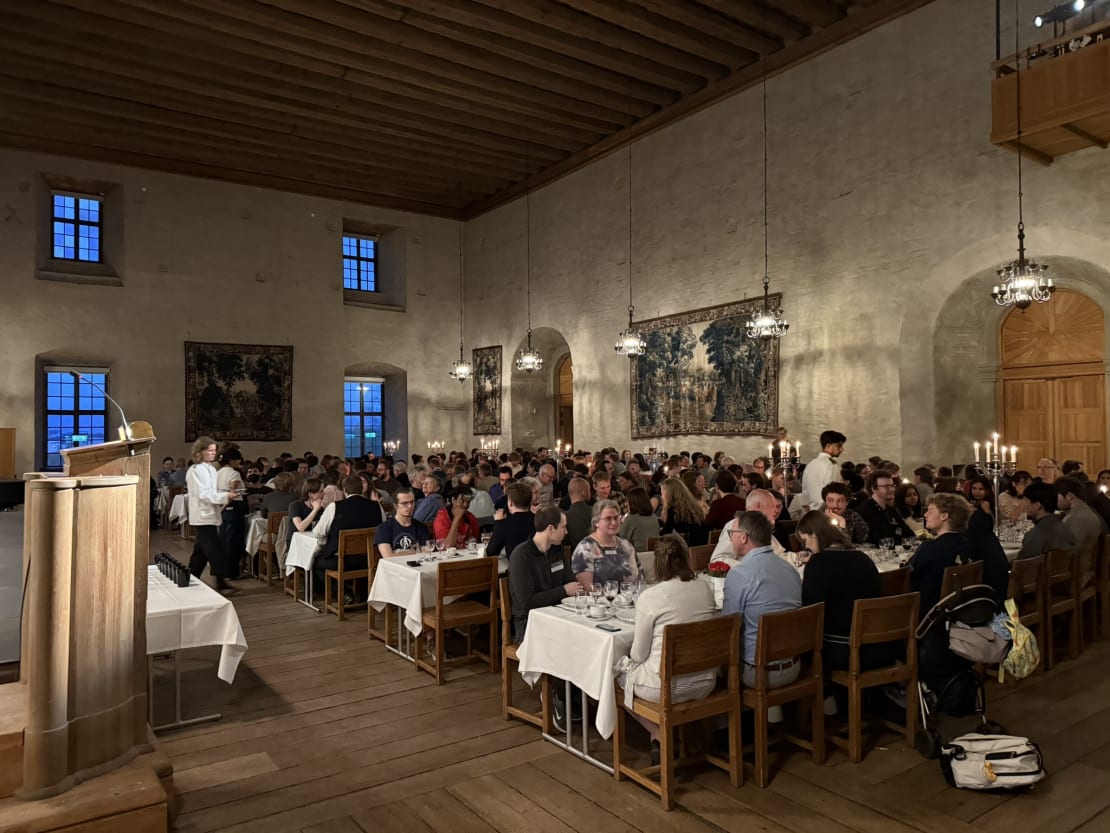 People sitting at tables inside of a castle.