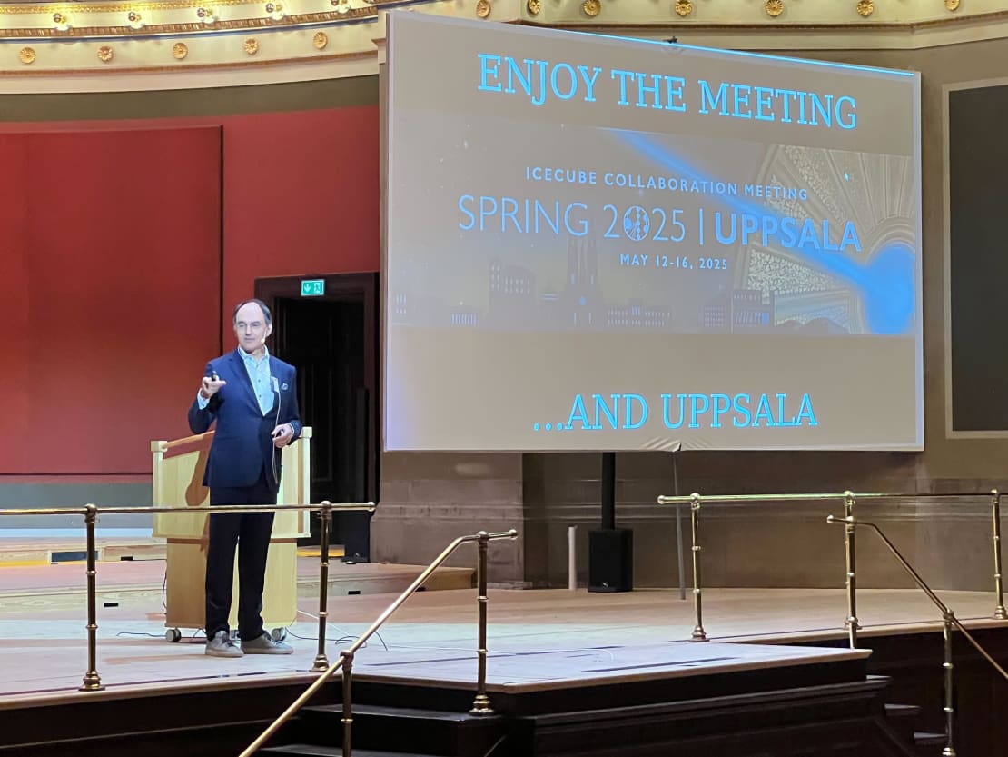 A man on stage giving a talk next to a screen.
