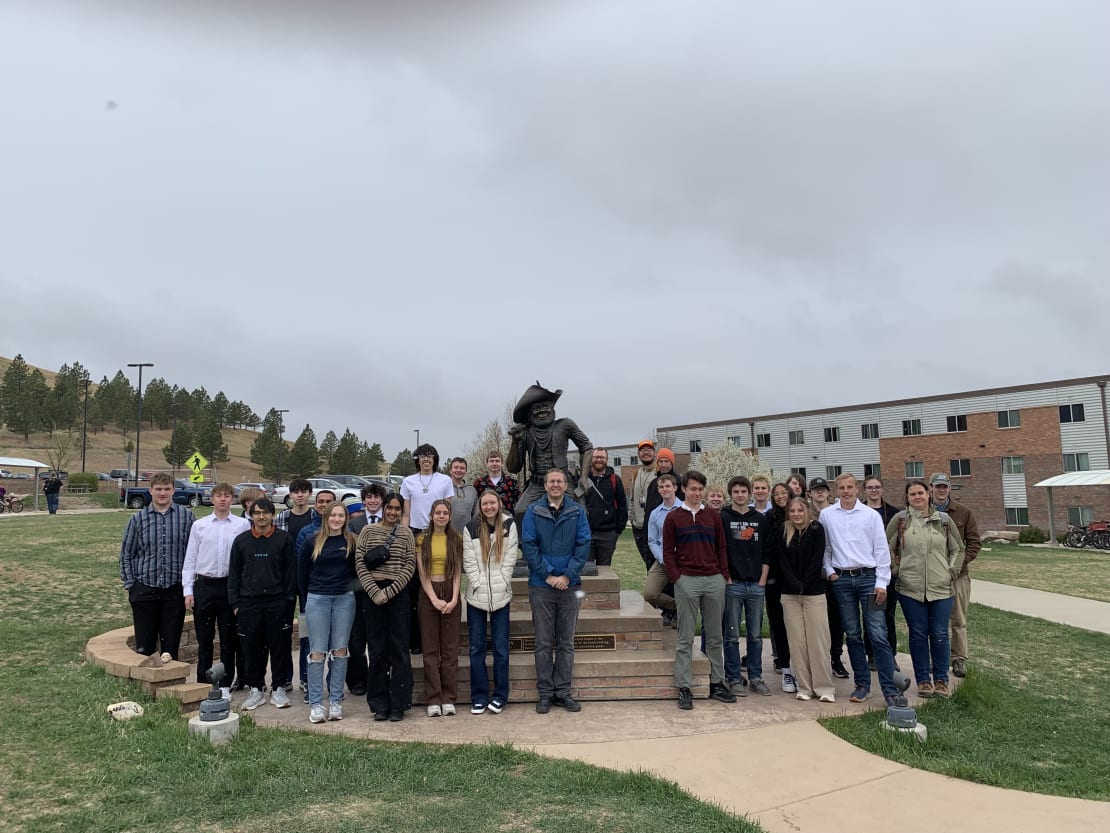 People posing in front of a statue