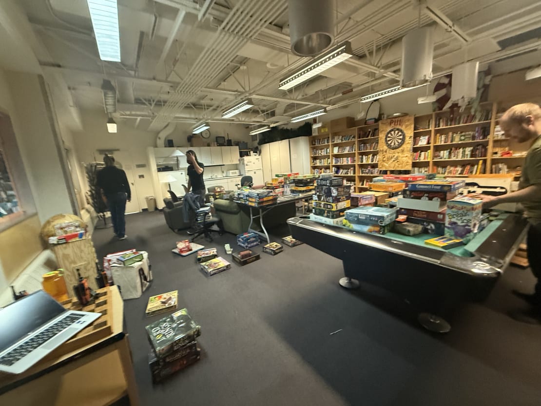 Game room at the South Pole in the midst of board game organizing, with stacks of board games on the pool table, the floor, etc.
