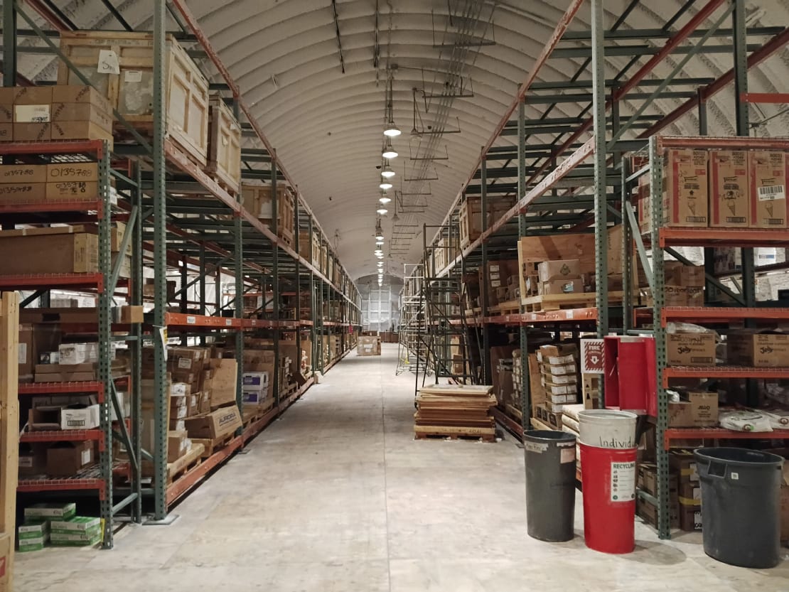 View down corridor of cold storage facility, both sides lined with shelves.
