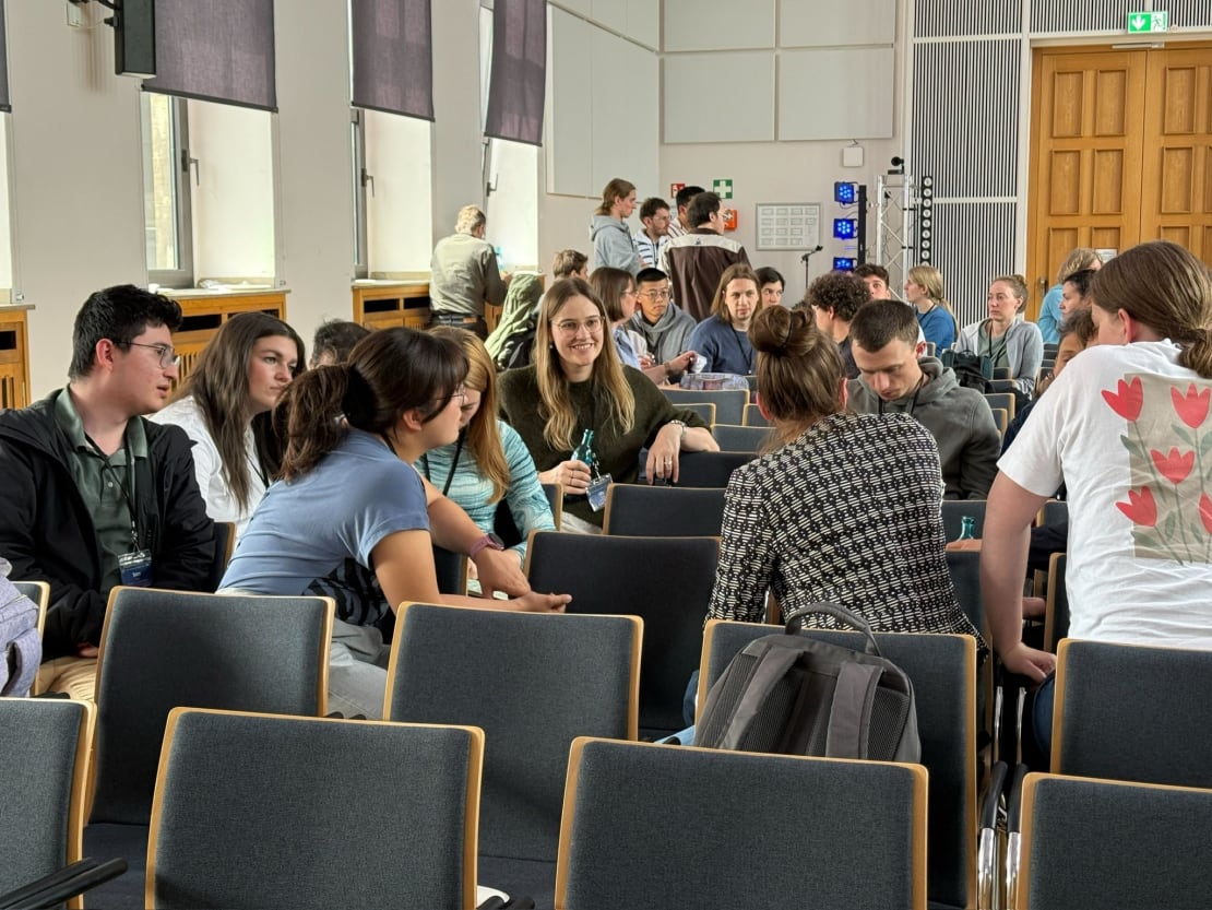 A group of people sitting in auditorium chairs talking to each other.