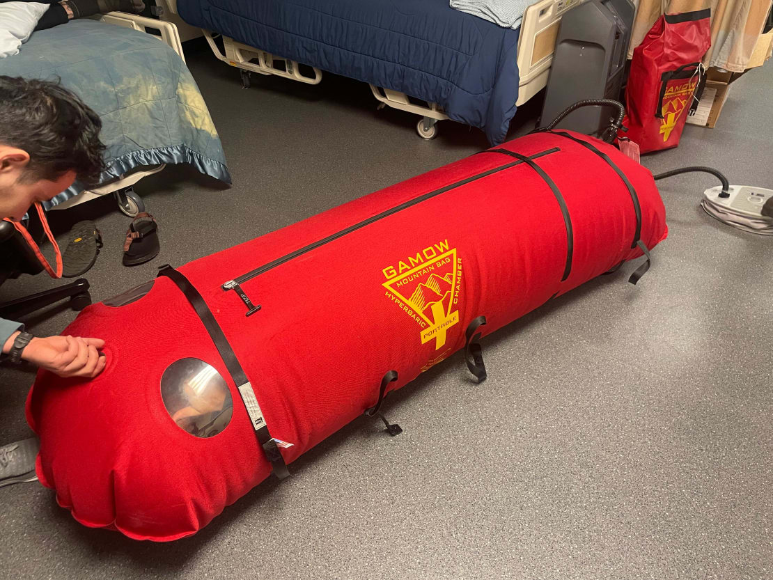 Long red medical-training bag, inflated on the floor.