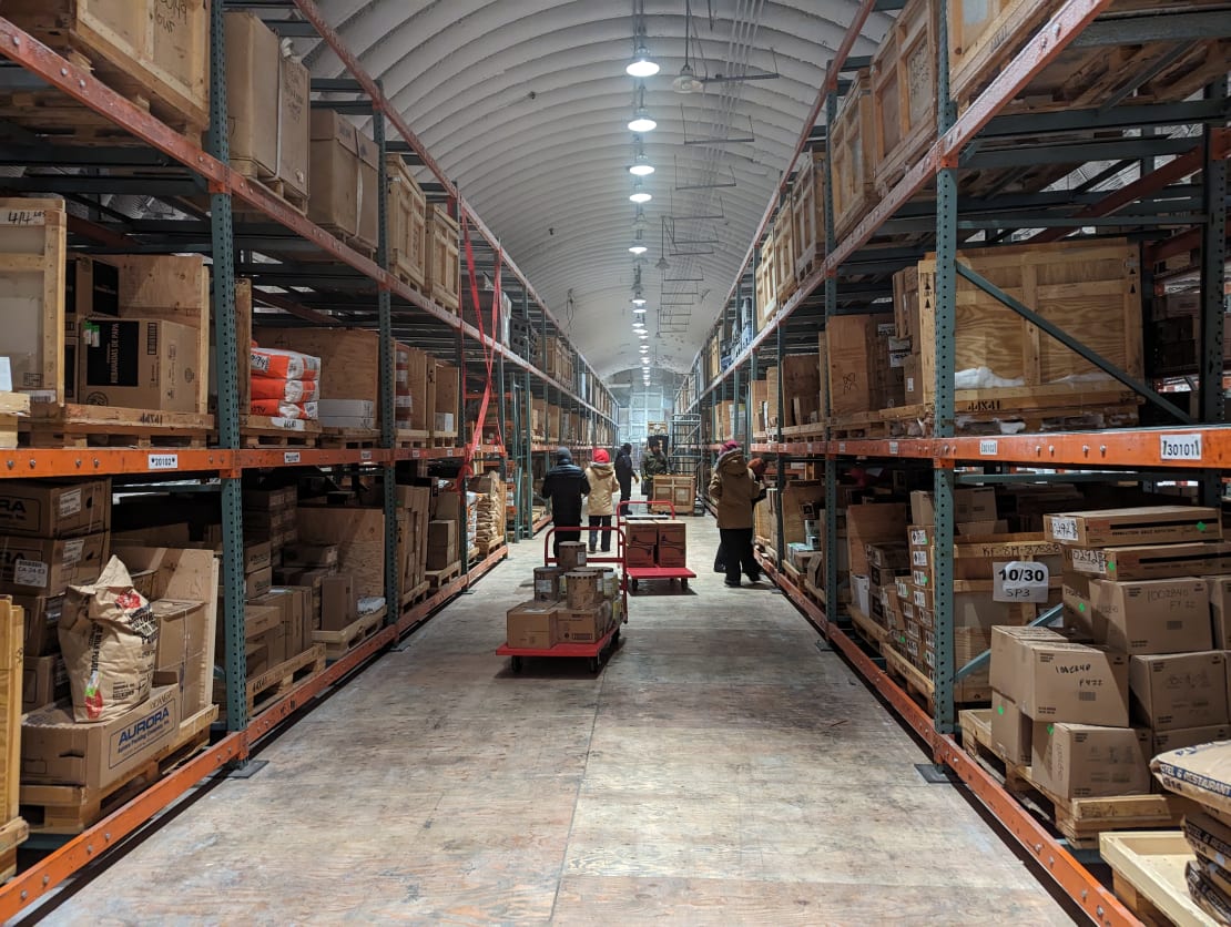 Long view of storage aisle with tall shelves filled with crates and boxes.
