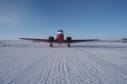 Front view of a Basler plane parked on the ice at the South Pole under blue skies.