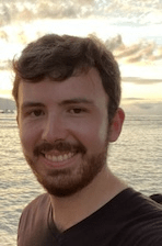 A person smiling with the sun and clouds in the background.