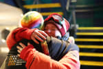 Close-up of two people in cold-weather outerwear hugging good-bye.