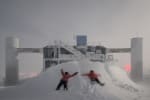 Two winterovers making snow angels in large snowdrift in front of the IceCube Lab.