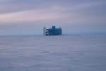 The IceCube Lab seen from a distance, with a darkening cloudy sky before sunset.