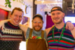 Close-up on three people smiling for the camera, wearing colorful shirts.