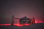 IceCube Lab in winter, backlit in red lights, starry sky overhead.