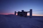 The IceCube Lab in shadow at twilight, with orange light just beginning to appear on horizon.