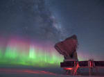 Side view of the South Pole Telescope at night, with low bright auroras and the Milky Way overhead.
